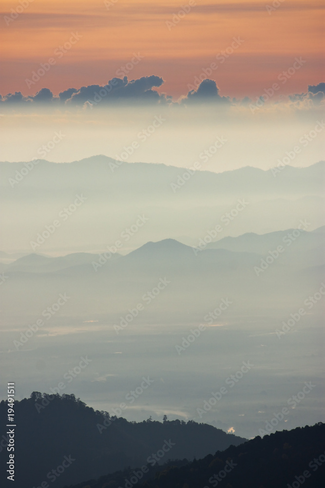 Obraz premium Foggy morning sunrise with high mountain background