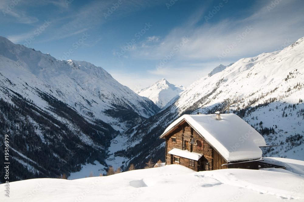 winterscene of alpine valley with snow coverd cabin