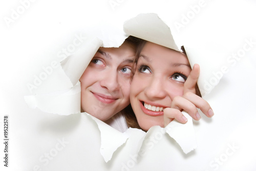 Vászonkép young couple peeping through hole in white paper