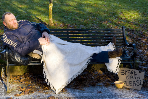homeless man sleeping on park bench
