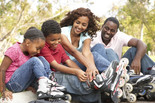 Family Putting On In Line Skates In Park