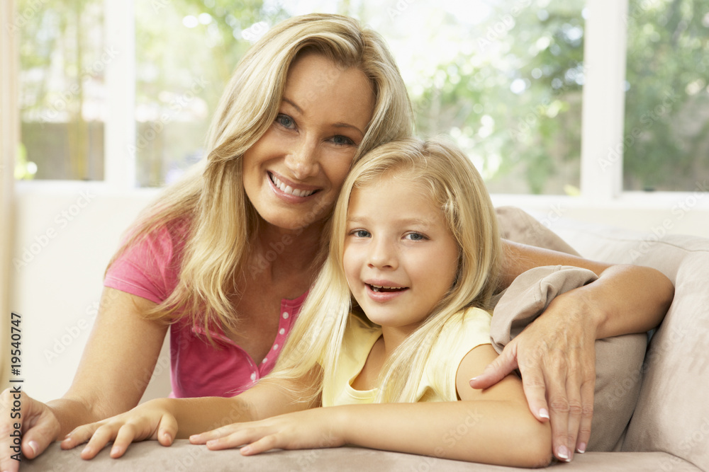 Mother And Daughter Relaxing On Sofa At Home