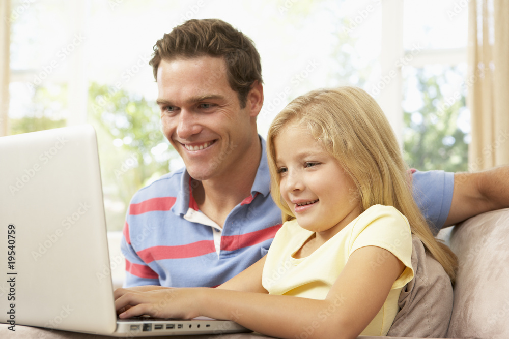 Father And Daughter Using Laptop At Home
