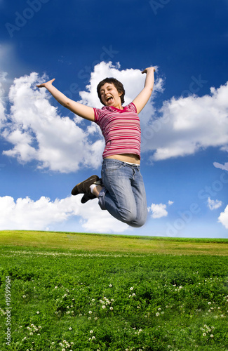 Young happy woman jumping high against blue summer sky