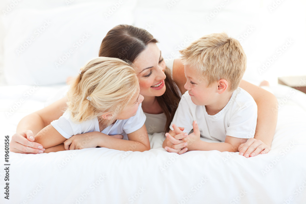 Merry children and their mom discussing lying on a bed Merry children and their mom discussing lying on a bed