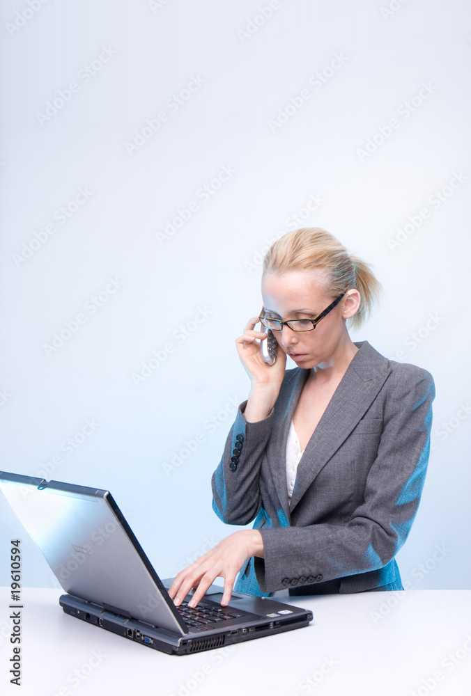 blonde businesswoman using laptop computer and mobile phone at blonde businesswoman using laptop computer and mobile phone at