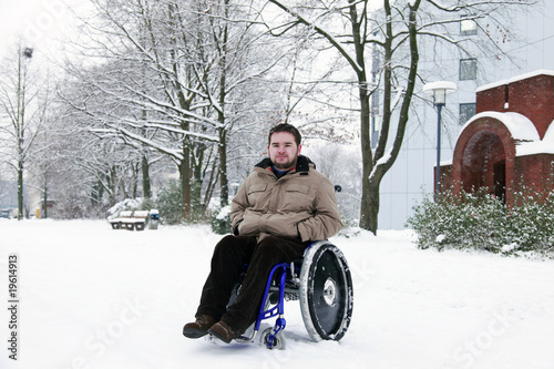 young man in wheelchair at the park on a cold winterday photo