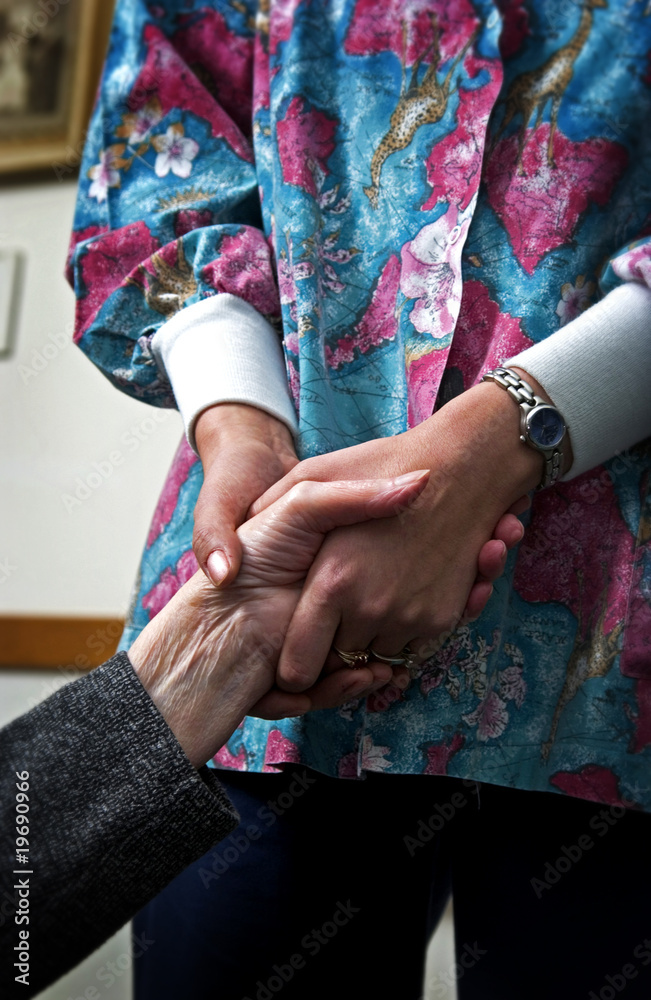 Nurse holding senior womans hand