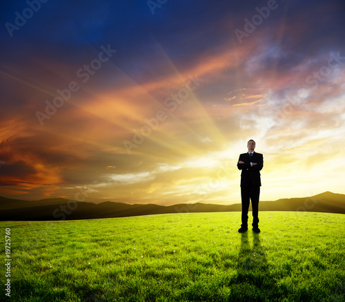 young businessman on green field and sunset