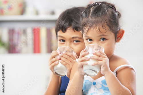 Two little boy and girl drinking milk