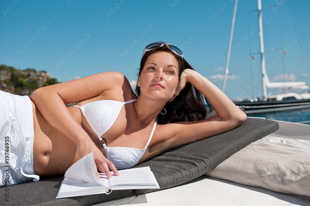 Obraz premium Attractive woman sunbathing on luxury boat