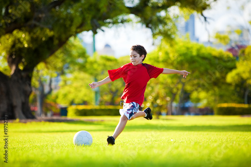 Young excited boy kicking ball in the grass © Martin Valigursky