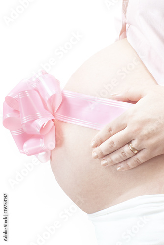 Side view of pregnant woman belly with pink ribbon bow