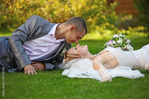 Newly-married couple lies on a grass