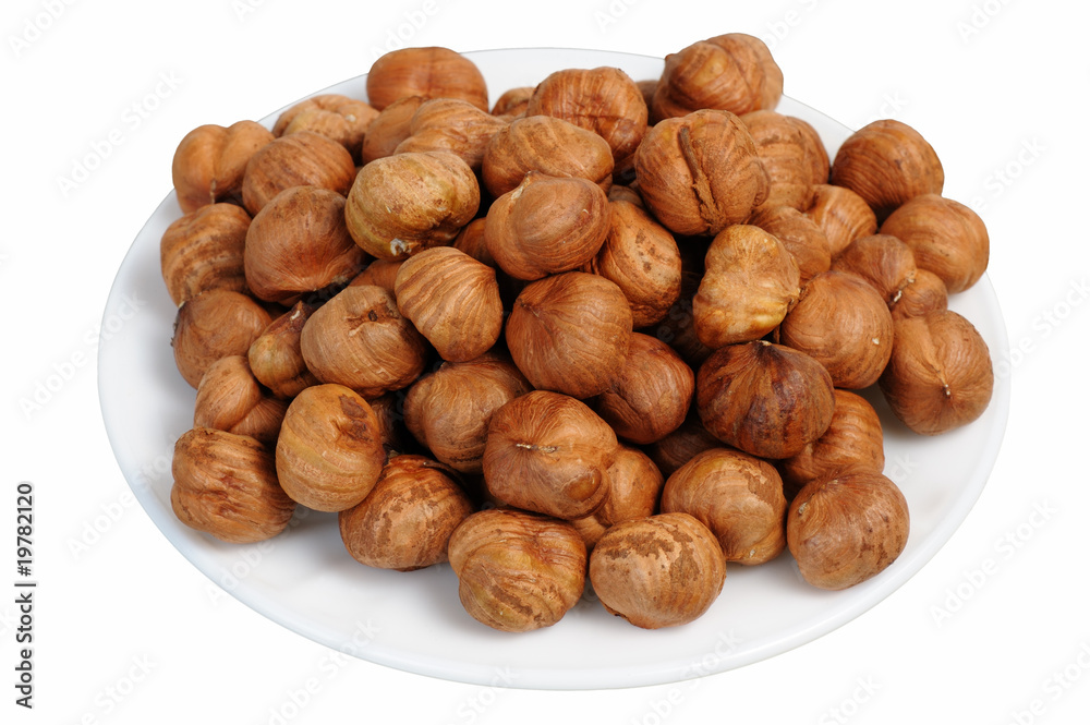 Hazelnuts on a white plate, isolated. Hazelnuts on a white plate, isolated.