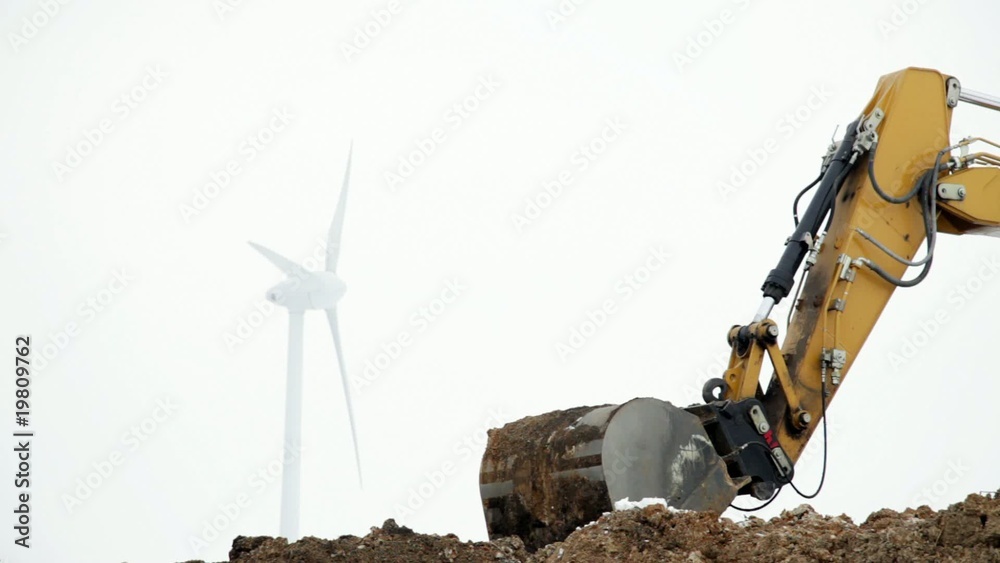 Baustelle mit Bagger und Windrad im Hintergrund