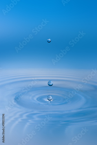 Clean blue drop of water splashing in clear water. Abstract blue