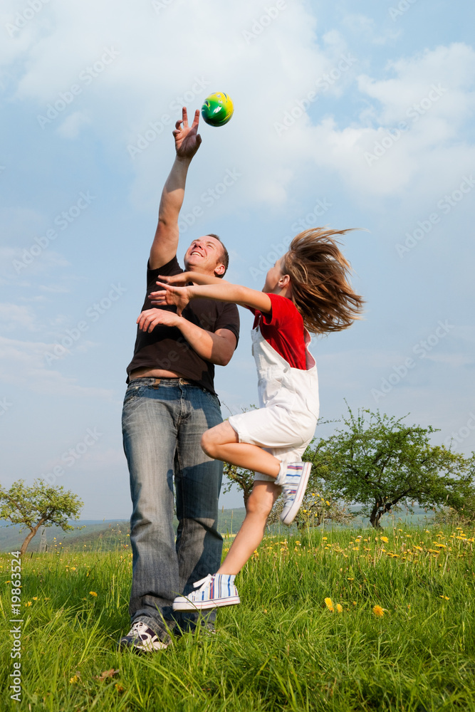 Vater und Kind fangen den Ball auf der Wiese