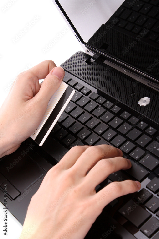 Closeup of men's hands holding credit cart by a laptop keyboard Closeup of men's hands holding credit cart by a laptop keyboard
