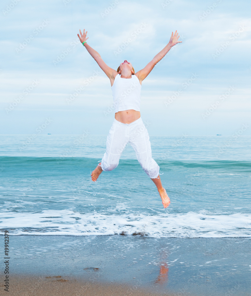 happy young woman is jumping in the beach