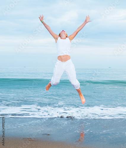 happy young woman is jumping in the beach