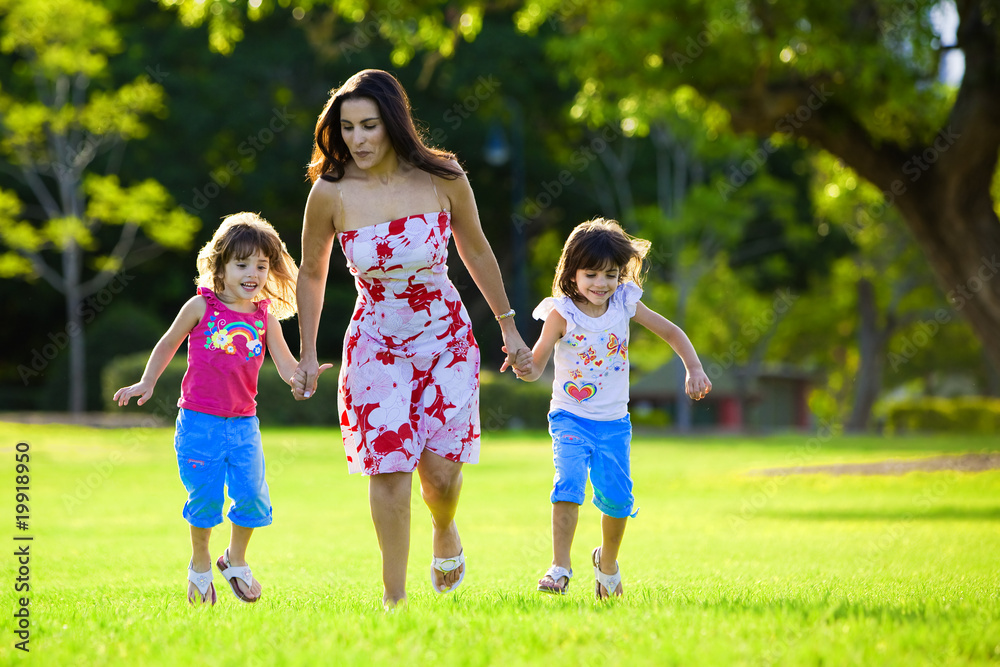 Fototapeta premium Excited mum and two daughters jumping in grass