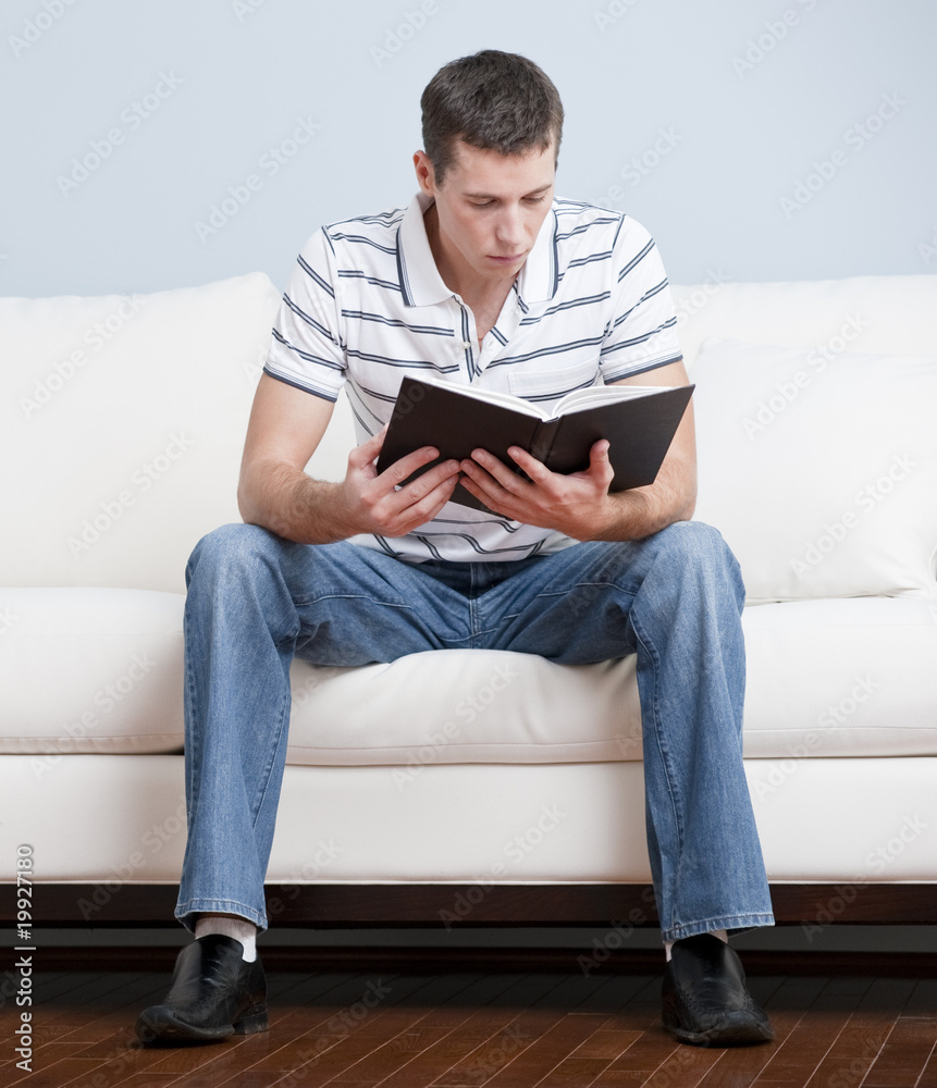 Young Man Sitting on Sofa Reading