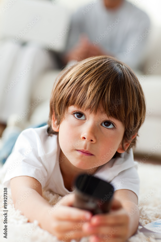 Concentrated little boy watching TV lying on the floor Concentrated little boy watching TV lying on the floor