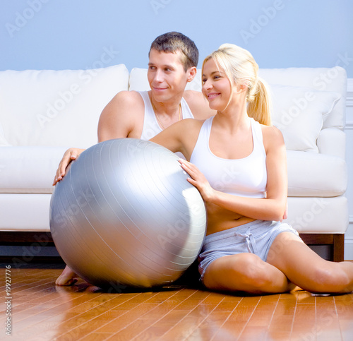 Couple Sitting on Floor With Silver Exercise Ball
