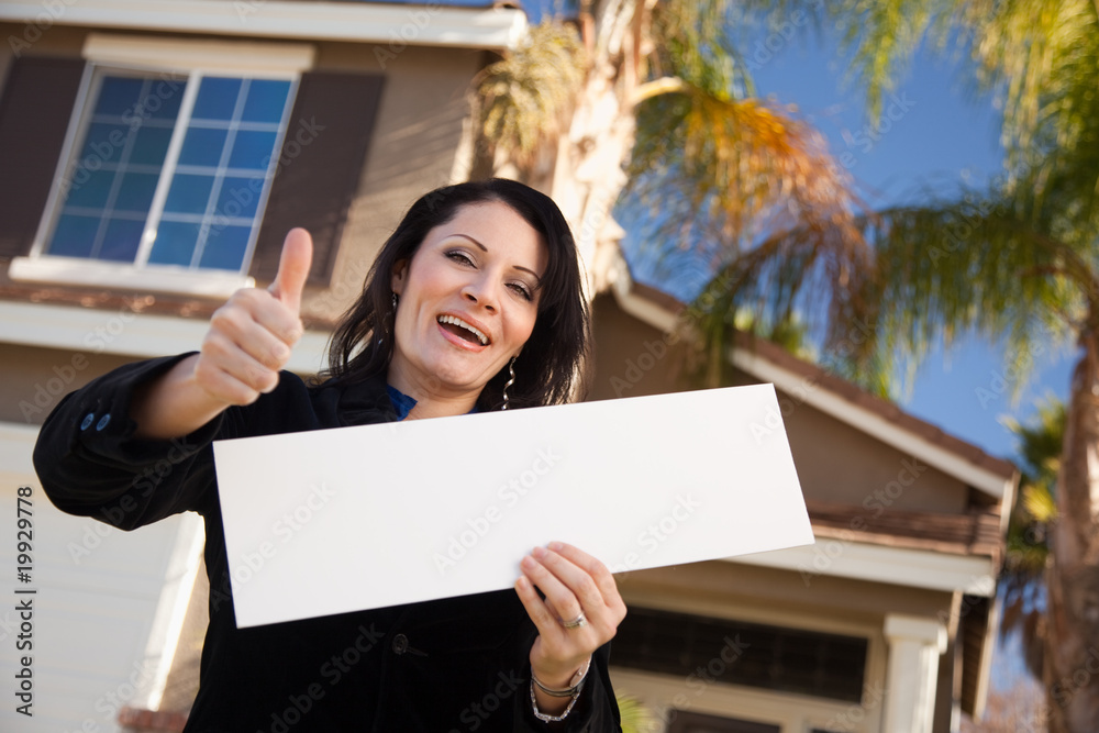 Attractive Hispanic Woman Holding Blank Sign in Front of House Attractive Hispanic Woman Holding Blank Sign in Front of House