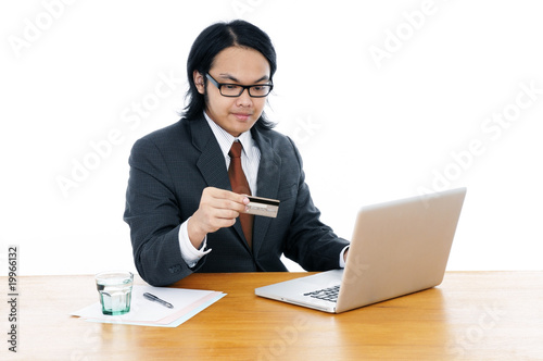 Young business executive holding credit card and using laptop