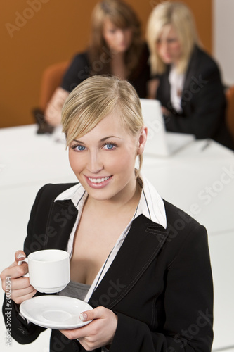 Blond Businesswoman Drinking Coffee In A Busy Office