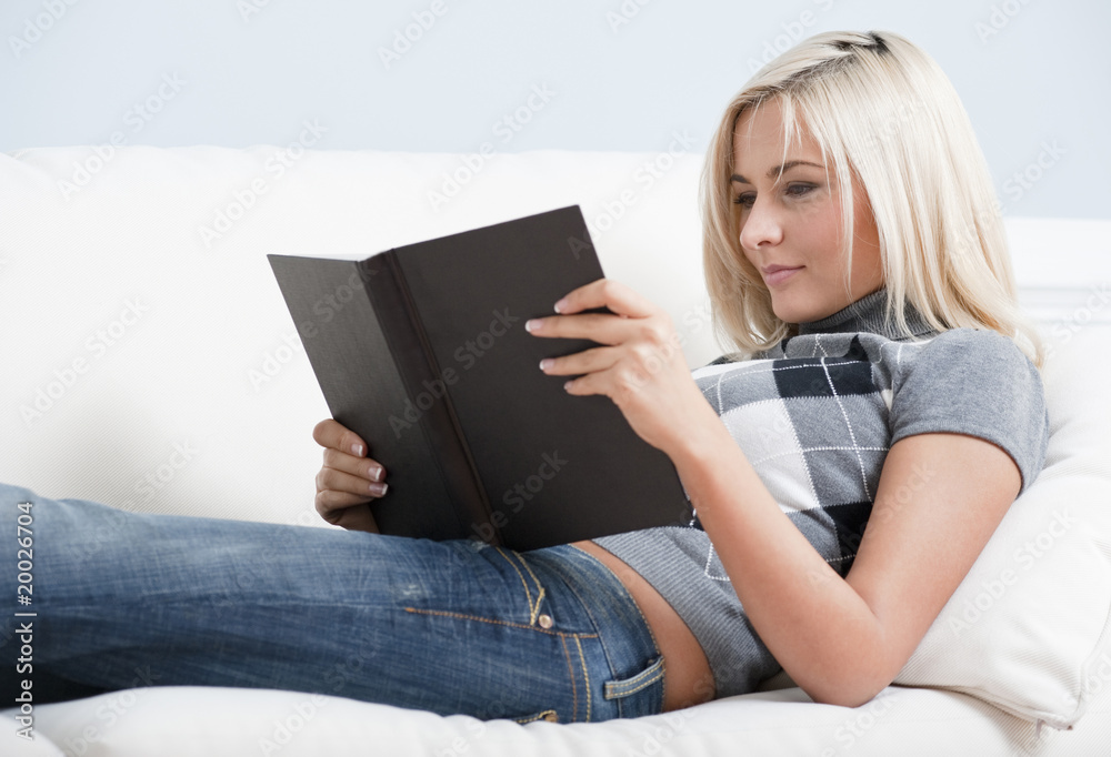 Smiling Woman Reading Book on Couch Smiling Woman Reading Book on Couch