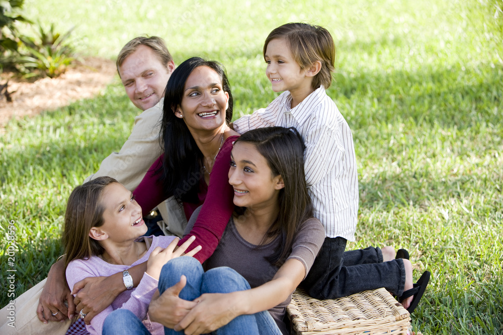 Happy interracial family of five enjoying a picnic in the park Happy interracial family of five enjoying a picnic in the park
