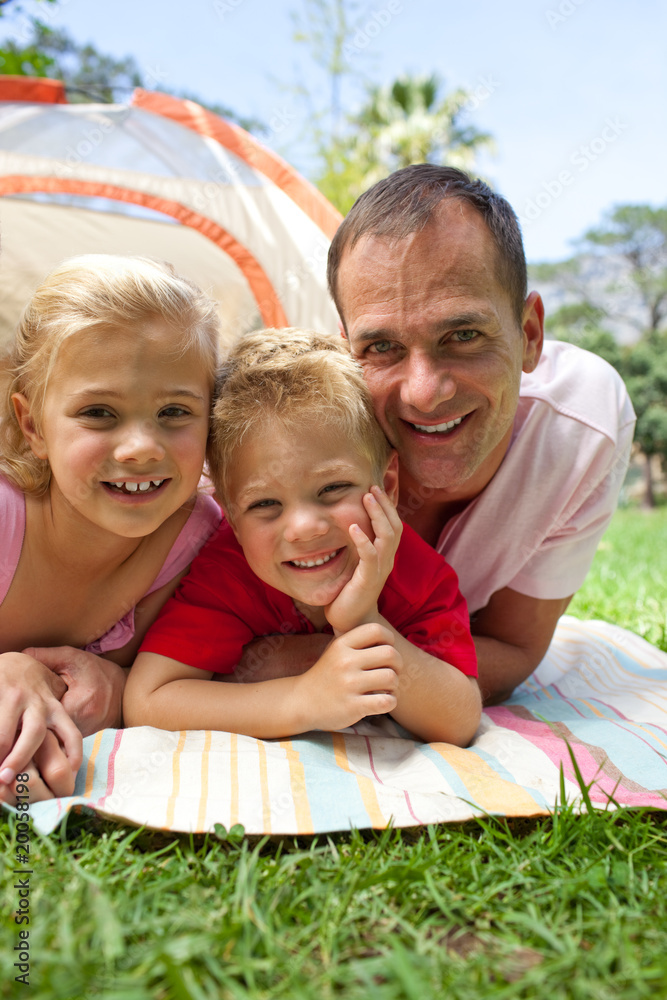 Fototapeta premium Happy father and his children lying on the grass