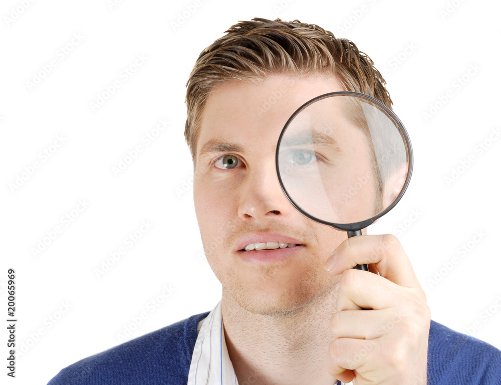 Male student looking through a magnifying glass Male student looking through a magnifying glass