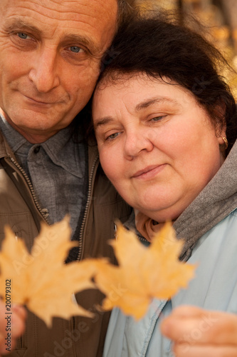 Serious middleaged man and woman hold maple leaves photo