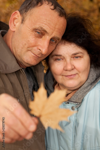 Old man and old woman look at maple leave photo