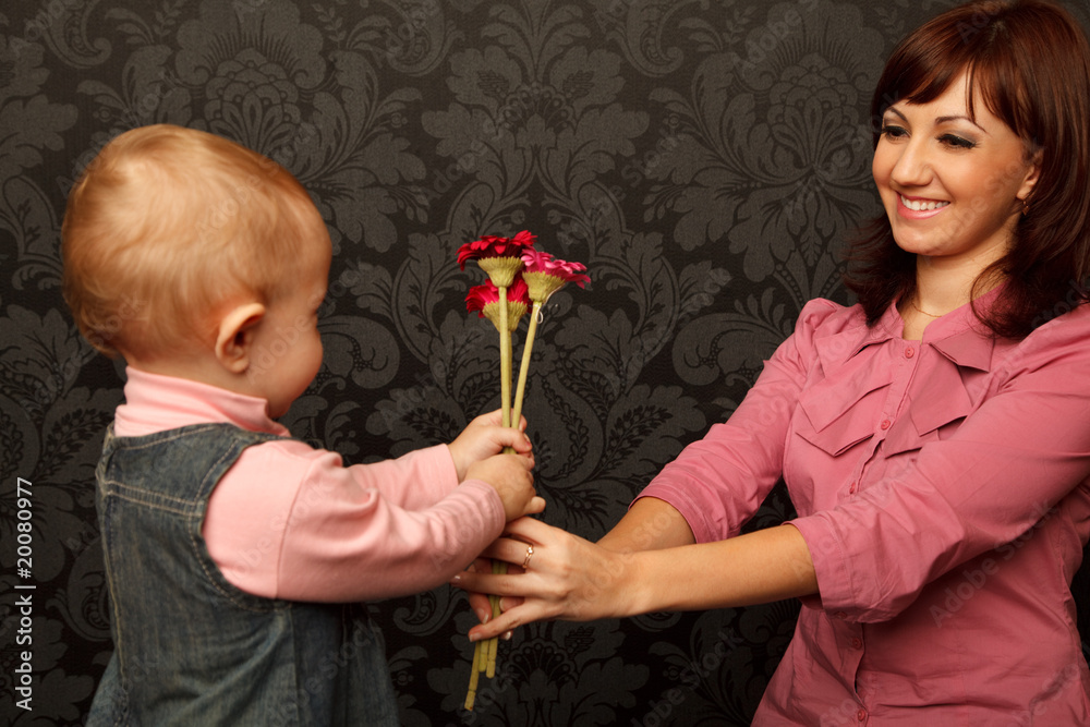daughter gives her mother flowers against wall with ornament daughter gives her mother flowers against wall with ornament