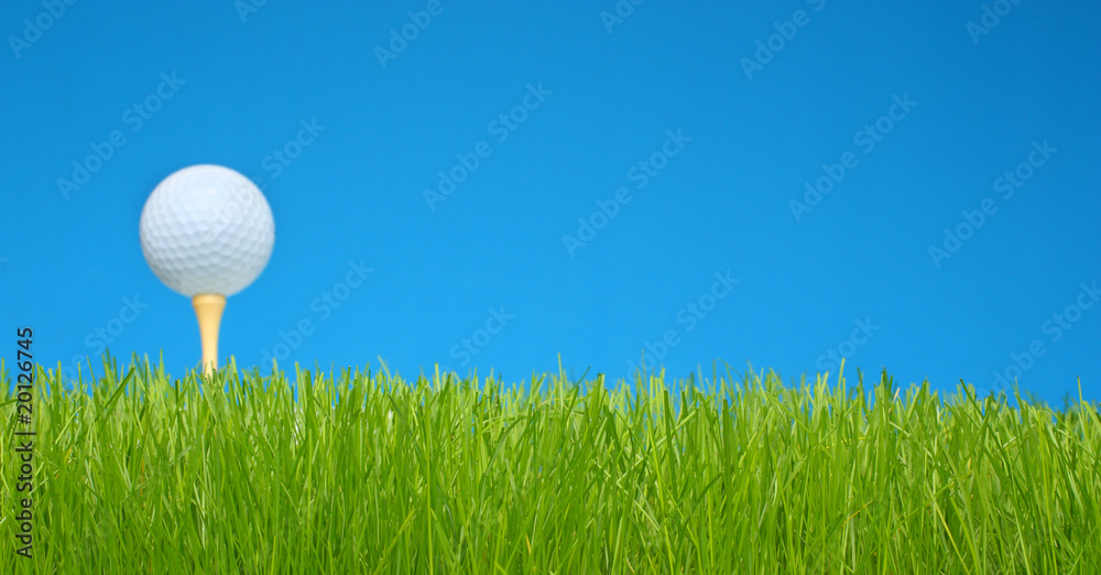 Golf ball on tee in a green grass field Golf ball on tee in a green grass field
