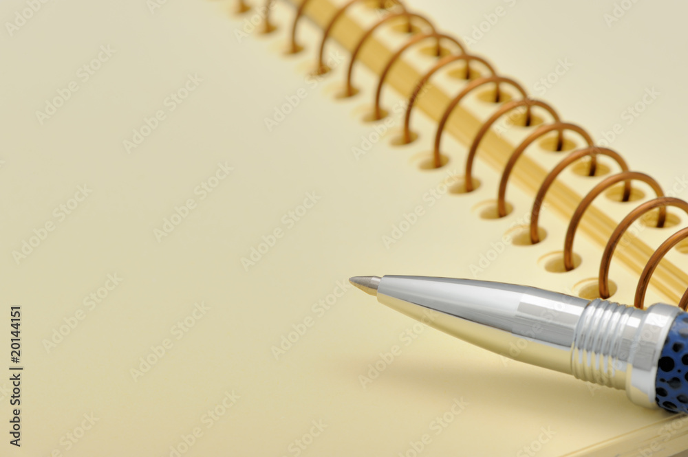 Pen and a notebook on a spiral with a yellow paper Pen and a notebook on a spiral with a yellow paper