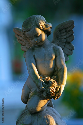A statue of a baby angel in a Christian cemetery