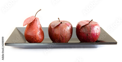 three fruits glued over with leaves on black tray