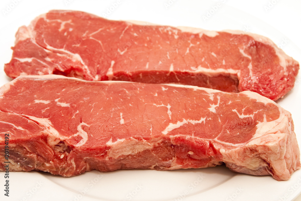 Two Prime Strip Steaks on a White Plate.