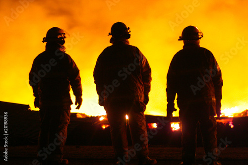 A silhouette of three fire fighters