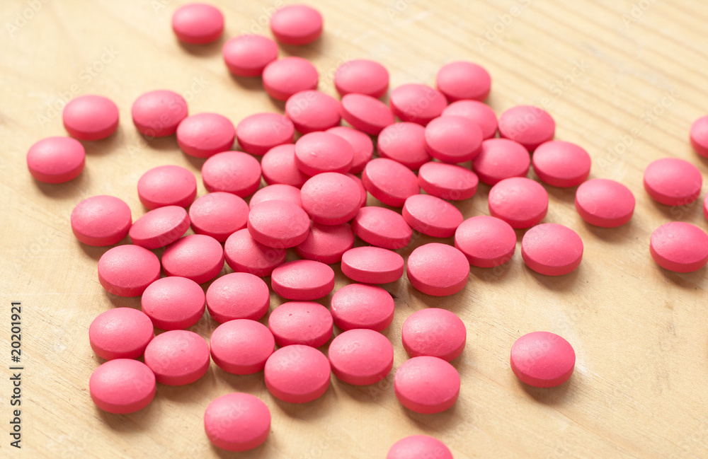 Pink pills on brown background. Shallow depth of field