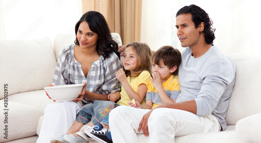 Smiling family watching TV on sofa Smiling family watching TV on sofa