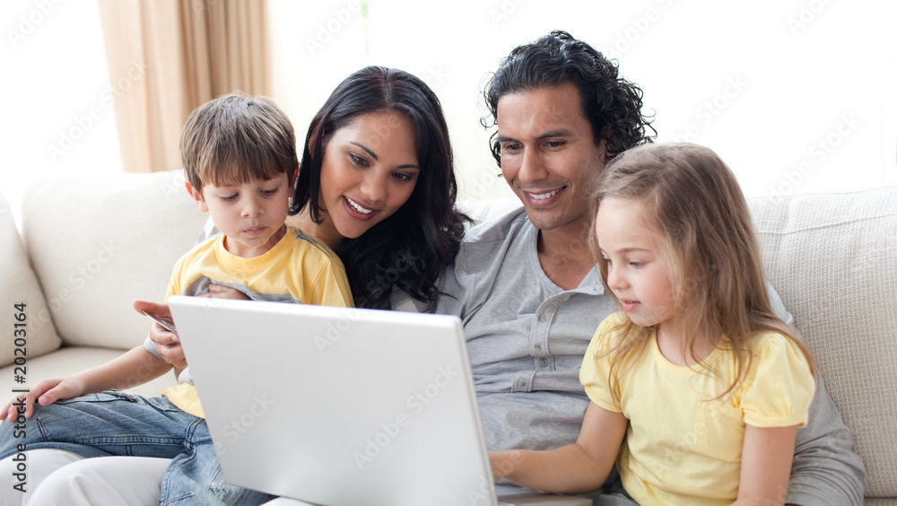 Affectionate parents using laptop with their children Affectionate parents using laptop with their children