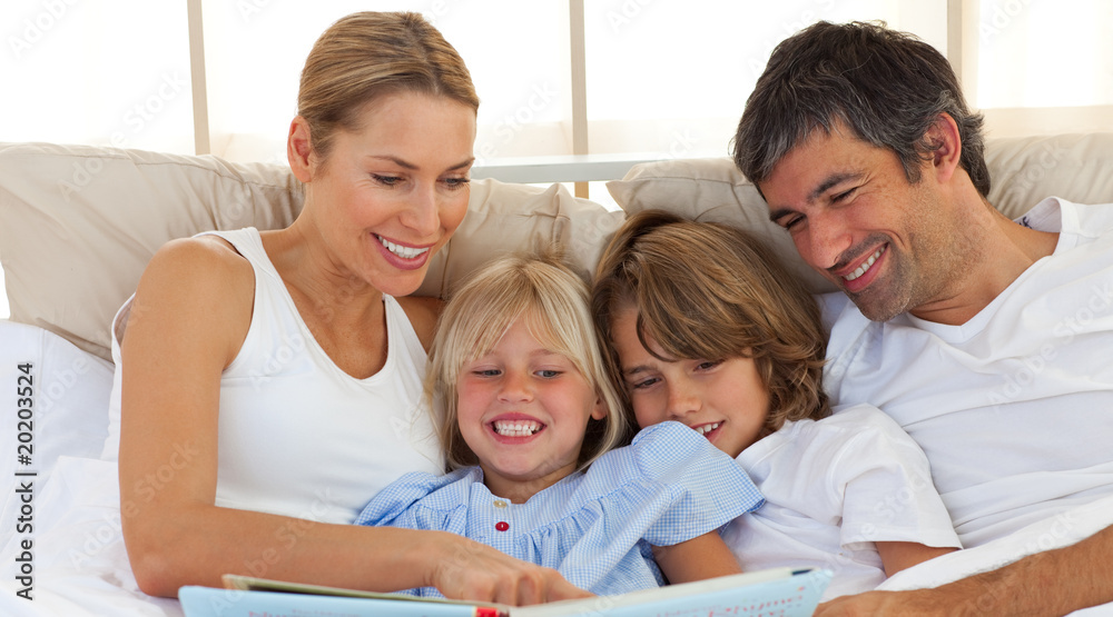 Joyful family reading a book on bed Joyful family reading a book on bed