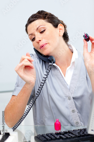 Talkative woman on phone painting her nails photo